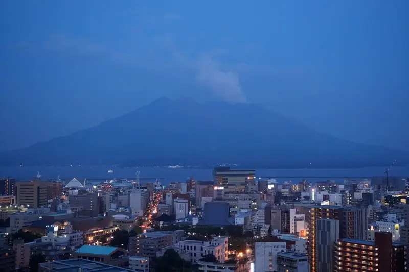 Sakurajima volcano looming over Kagoshima city at blue hour