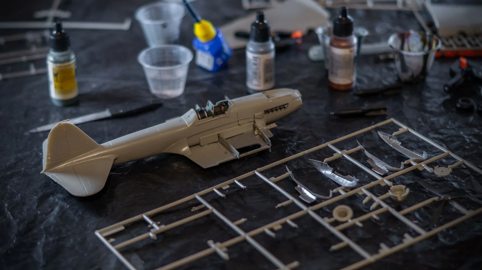 A scale model kit under assembly with tools and paints