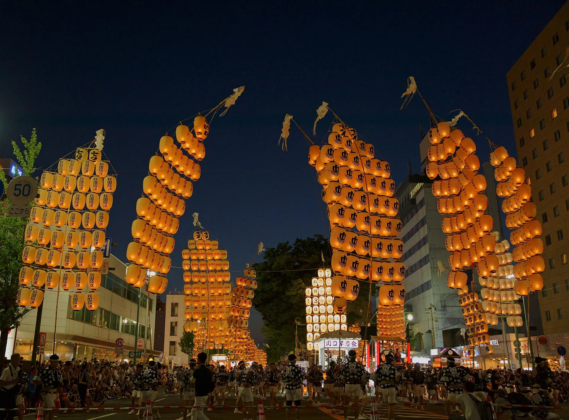 Glowing Kanto festival lantern poles balanced against the night sky in Akita